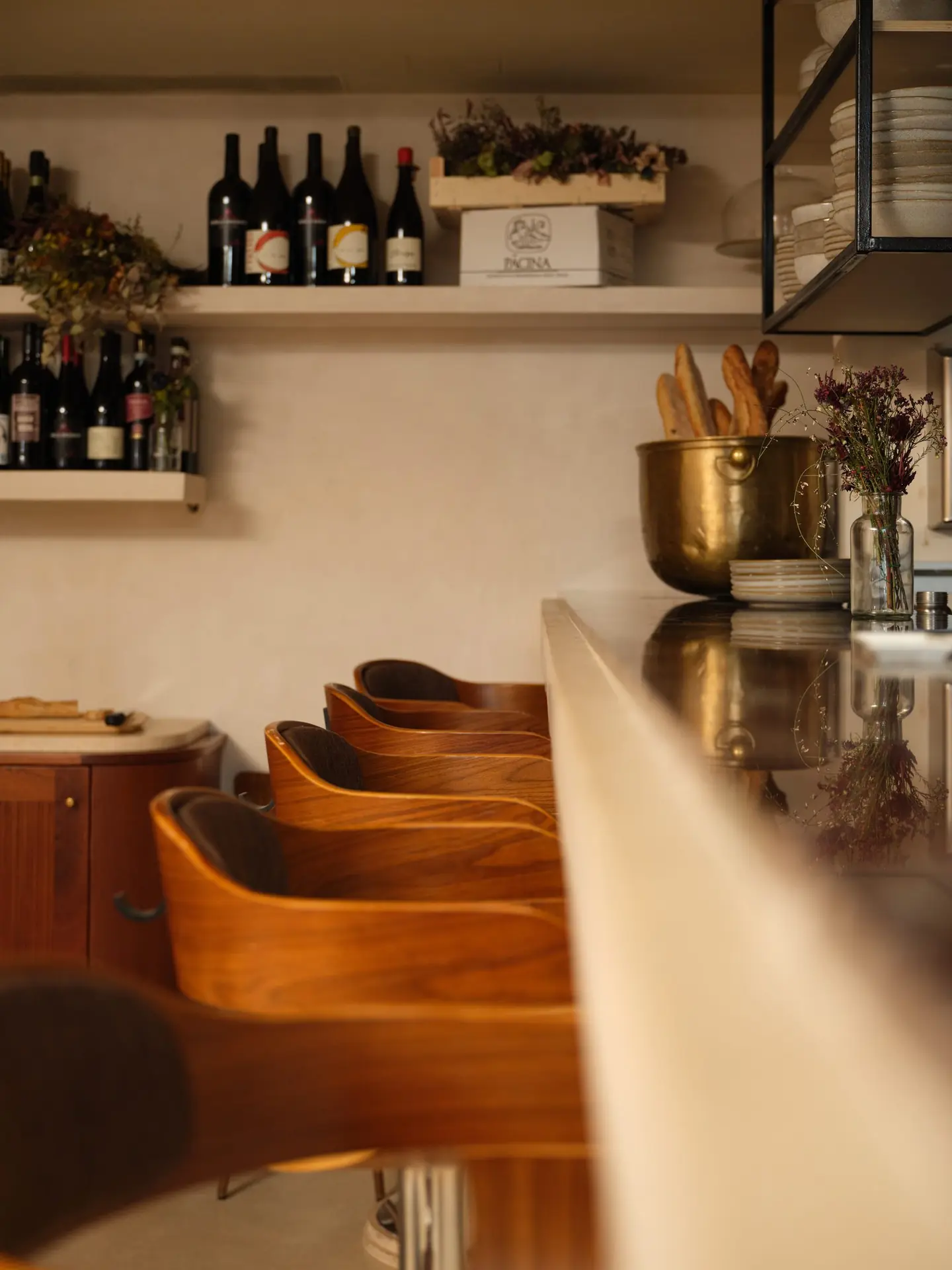 Étagères à vin, comptoir en marbre noir, banquettes en bois cintré