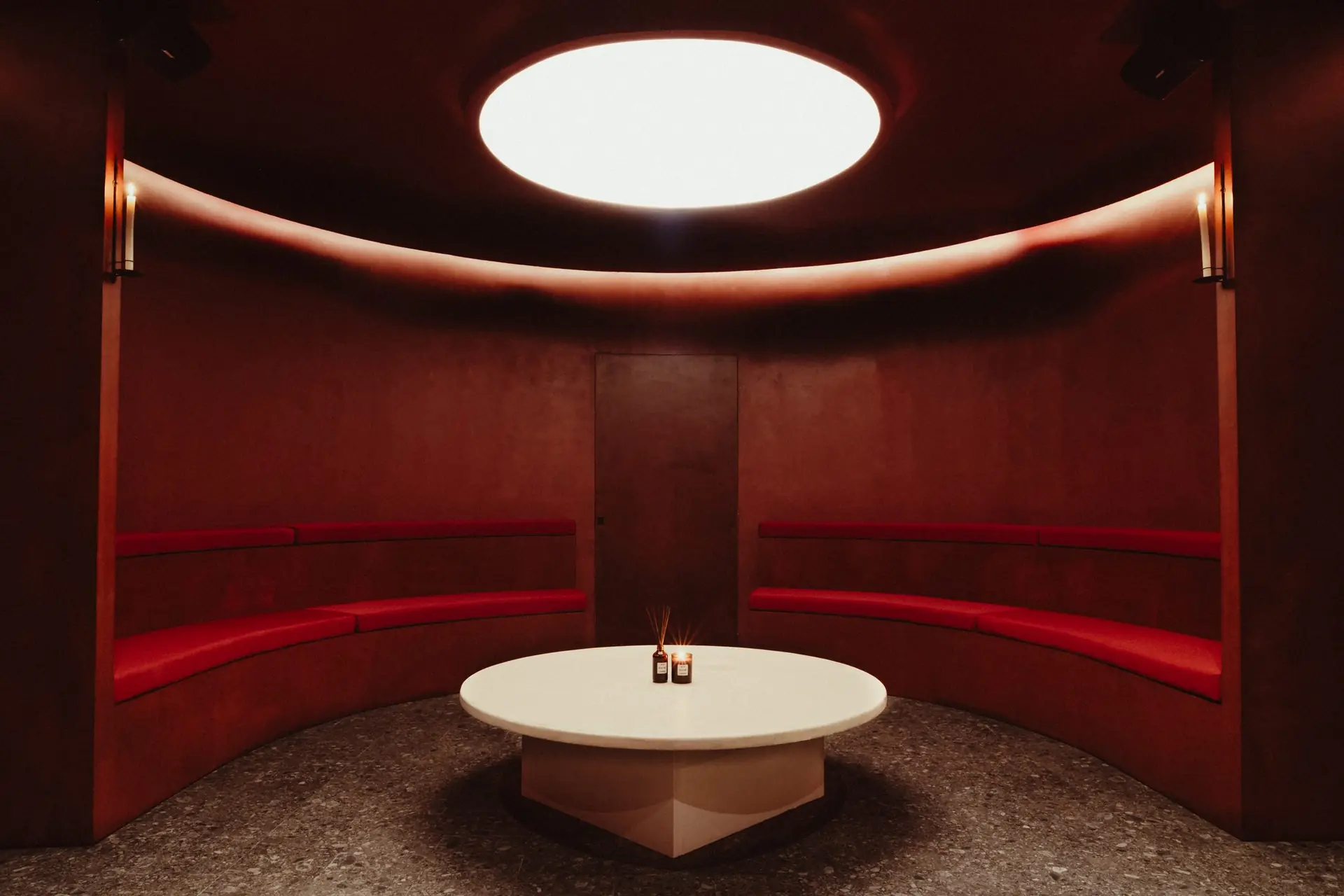 Salle circulaire rouge, oculus zénithal, banquette et table ronde
